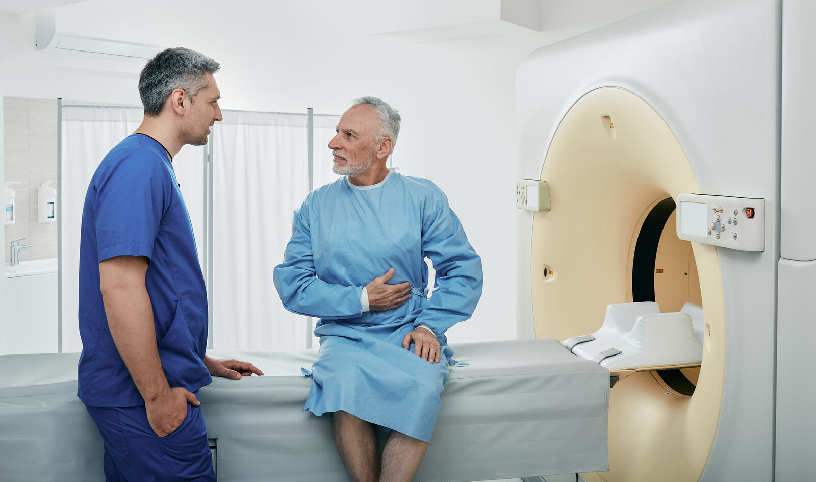 A radiologic technologist with a patient at a CT scanner